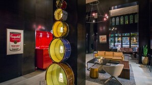 Un interior moderno con una exhibición de batería, un refrigerador rojo y una zona de estar acogedora con sofá y mesa de centro.
