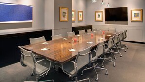 A conference room with a long table, chairs, framed pictures, and a television on the wall. - Sub Pop King | Vinyl Collection & City Views (Seattle)