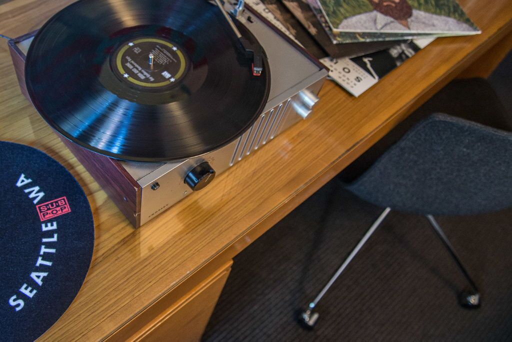 A turntable with a vinyl record on a wooden desk.