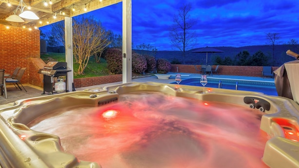 A hot tub with a glass enclosure, a barbecue grill, and a pool in the background. - Chattanooga Valley Paradise | Pickleball | Pool (flintstone)