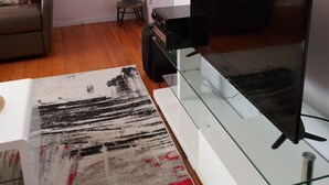 Un salon moderne avec un canapé, une table basse en verre, un téléviseur et une plante en pot.