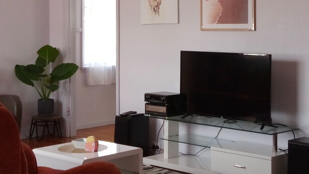 Un salon équipé d’un téléviseur à écran plat, d’un ventilateur de plafond, d’une plante en pot et d’œuvres d’art accrochées au mur.