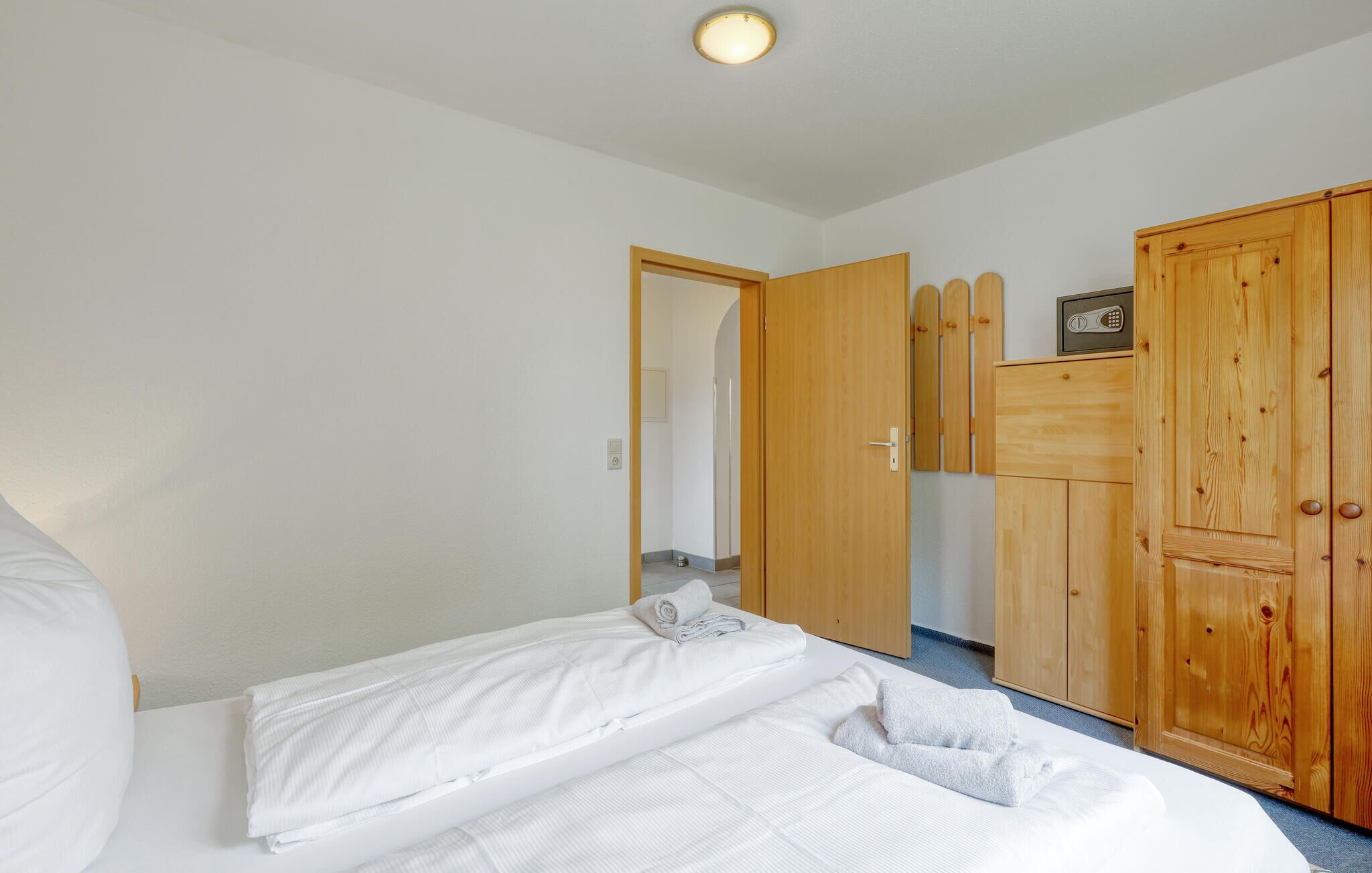 Ein Schlafzimmer mit Bett, Holzschrank und einer Tür zu einem anderen Raum.
