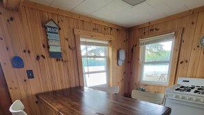 Een houten chalet met een eettafel, twee stoelen, een fornuis en uitzicht op de omgeving.