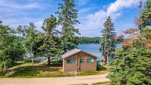 Eine Holzhütte mit Metallbedachung, umgeben von Bäumen und einem See.