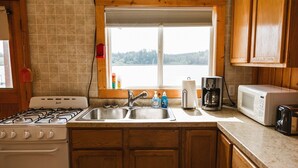 A kitchen with a gas stove, double sink, and wooden cabinets. - Cabin #4 - Classic Americana (Lake Emma Township)