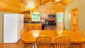 A wooden cabin with a dining area, kitchen, and a ceiling fan. - Cabin #6 - Loons' Nest (Lake Emma Township)