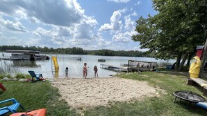 A lakeside setting with a sandy beach, a dock, and a small docked boat. - Cabin #6 - Loons' Nest (Lake Emma Township)