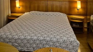 A hotel room with a large bed, wooden headboard, two bedside tables with lamps, and three framed artworks on the wall. - Flat com Cozinha Completa em Hotel Slaviero em Moema (Indianópolis São Paulo)