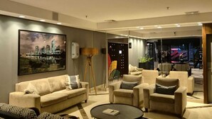 A modern living room with a sofa set, a coffee table, and a large cityscape painting on the wall. - Flat com Cozinha Completa em Hotel Slaviero em Moema (Indianópolis São Paulo)