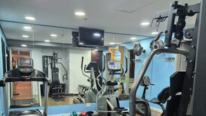 A gym with cardio equipment, weight machines, and a mirror. - Flat com Cozinha Completa em Hotel Slaviero em Moema (Indianópolis São Paulo)