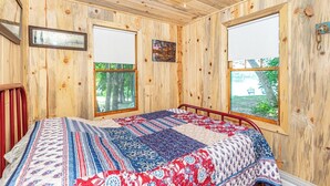 A wooden-paneled room with a bed, two windows, and a ceiling fan. - Cabin #7 - Gone Fishing (Lake Emma Township)
