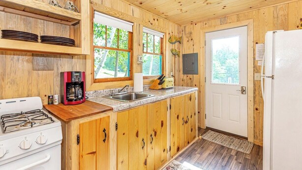 A wooden cabin kitchen with a gas stove, coffee maker, sink, and a refrigerator. - Cabin #7 - Gone Fishing (Lake Emma Township)