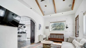 A spacious living room with a large flat-screen TV, a wooden coffee table, a sofa, and a patterned rug. - Aspen Grove Cabin w/Hot Tub (Fairplay)