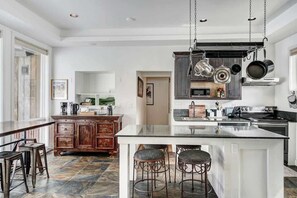 Una cucina moderna con isola centrale, mobili in legno scuro e pentole appese.