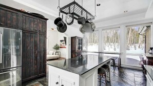 A spacious kitchen with dark wooden cabinets, a large island, and a hanging pot rack. - Aspen Grove Cabin w/Hot Tub (Fairplay)