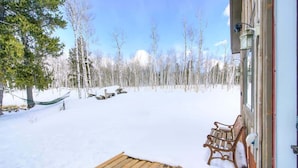 A wooden deck with a bench, a hammock, and a snow-covered yard with trees. - Aspen Grove Cabin w/Hot Tub (Fairplay)