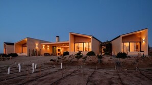 A modern, two-story house with a flat roof and large windows, surrounded by a landscaped garden with cacti and rocks. - Casa Vall Luxury Valley Life (FRANCISCO ZARCO EL PORVENIR)