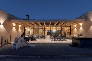 En moderne udendørs terrasse med legeområde, siddepladser og grillfaciliteter.