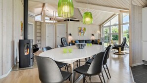 Uma sala de jantar moderna com uma grande mesa redonda, cadeiras pretas e luminárias pendentes verdes.