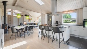 Cozinha moderna com ilha central, banquetas de bar e área de refeições com mesa e cadeiras.