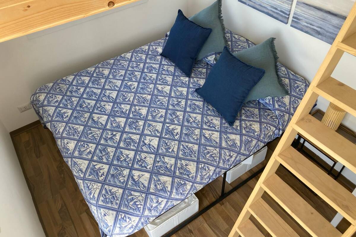 A bed with a blue and white patterned bedspread, two pillows, and a wooden headboard.