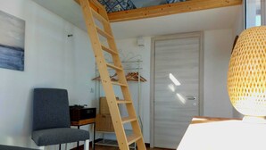 A room with a wooden ladder, a grey chair, a desk with a stereo, and a door. - BnB NOTO - Charming Guest House (Avola)