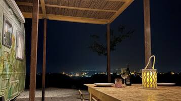 Un espacio de estar al aire libre cubierto con una mesa, sillas, una botella de vino y un candelabro.