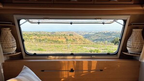 A cozy RV interior with a large window offering a scenic view of a hilly landscape. - BnB NOTO - Charming Guest House (Avola)