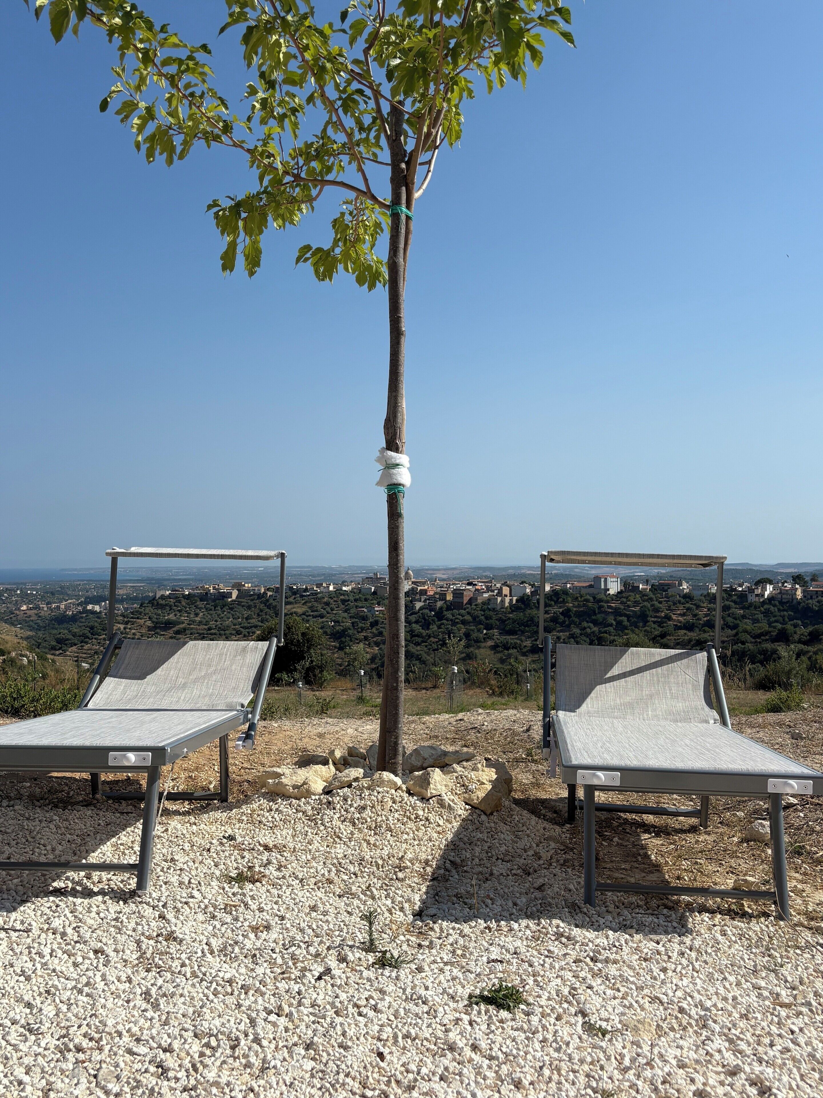Dos tumbonas con vista a un pueblo a lo lejos.
