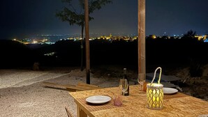 An outdoor dining area with a view of a city at night. - BnB NOTO - Charming Guest House (Avola)