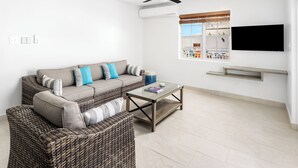 En moderne stue med sofa, sofabord og et fjernsyn monteret på væggen.