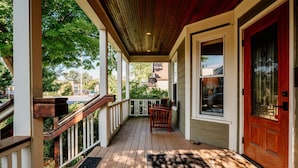 A wooden porch with a red door, white railings, and a bench. - NEW Luxe on Front Downtown (Traverse City)
