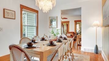 Une salle à manger avec une longue table en bois, dressée pour six personnes, entourée de chaises en osier.