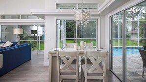 Una cocina moderna con comedor, ventanas amplias y vista a una piscina.