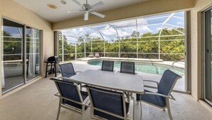 A covered outdoor area with a pool, a table with chairs, and a ceiling fan. - Salty Sands - walk to Manasota Beach pool home (Englewood)
