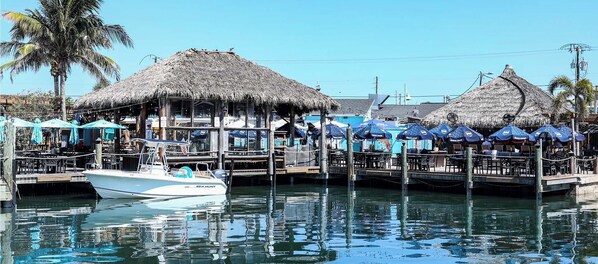 Un bote amarrado, una estructura con techo de paja y una fila de sombrillas.