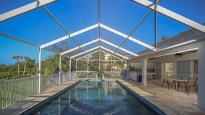 A covered swimming pool with a clear view of the surrounding landscape, a patio area with outdoor furniture, and a modern architectural design.