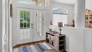 A spacious entryway with a double door, a wooden console table, and a large window providing a view of the outdoors.