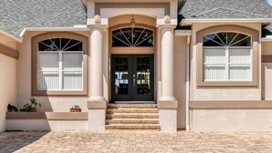 A two-story house with a symmetrical facade, a central entrance with steps, and a covered porch area.