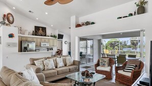 A spacious living area with a sofa set, a glass coffee table, and wicker chairs.