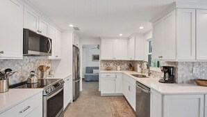 Una cocina moderna con armarios blancos, electrodomésticos de acero inoxidable y un salpicadero de azulejos.
