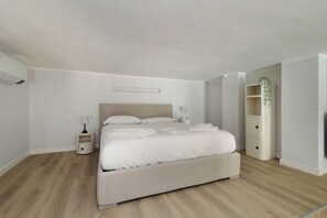 A bedroom with a bed, bedside tables, a nightstand, a lamp, a plant, and a built-in shelving unit. - Modern Sunlit Loft-Milan Retreat (Milano)