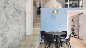 Ein modernes Interieur mit einer Treppe, einem Essbereich mit rundem Tisch und Stühlen sowie einer Wand in Blautönen.