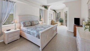 Un dormitorio con una cama grande, mesitas de noche, un televisor y un espejo.