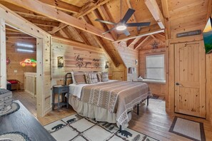 Un dormitorio de cabaña de madera acogedor con una cama, un ventilador de techo, una ventana y un letrero de neón.