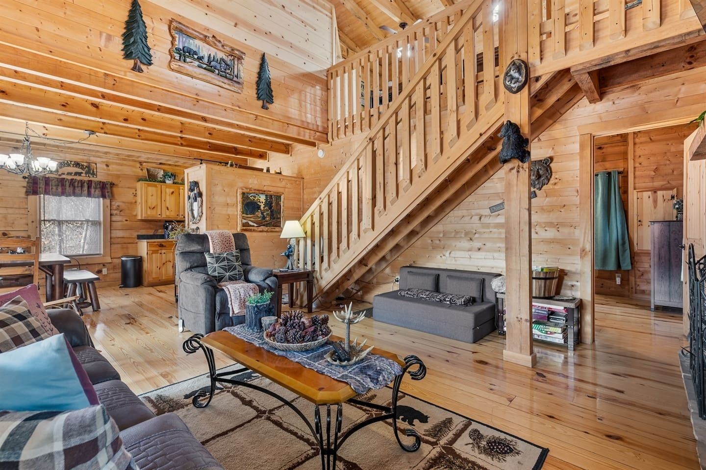 A log cabin interior with a staircase, wooden floors, a sofa, a coffee table, and a dining area.