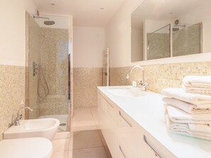 A modern bathroom with a glass-enclosed shower, a double sink vanity, and a large mirror.