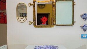 A white table with a blue patterned bowl, a wall-mounted mirror, and a lantern. - 50 steps from the Mare Superior (Orbetello)