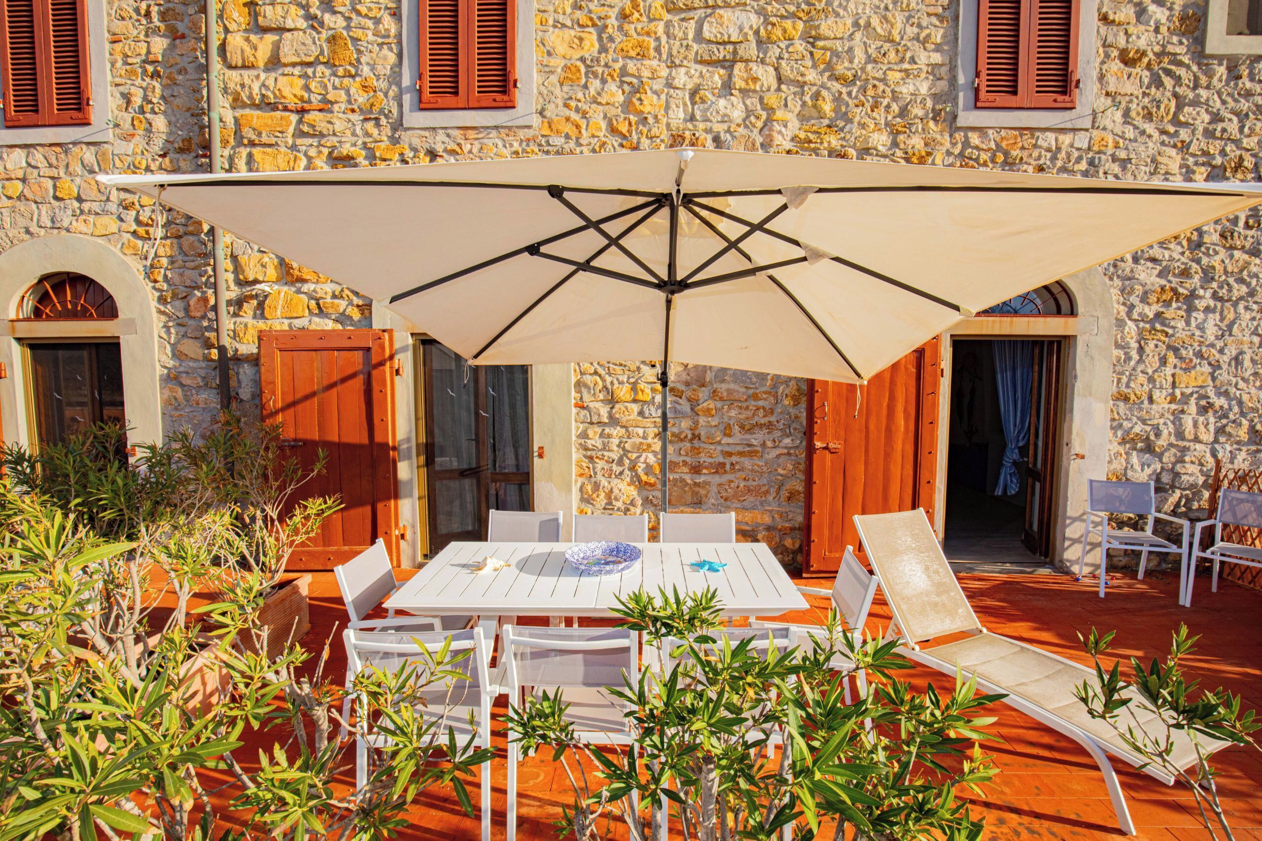A stone building with a patio area featuring a table, chairs, and an umbrella.